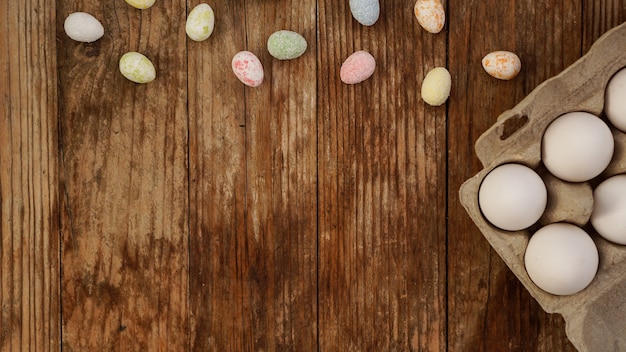 Chicken eggs in a cardboard tray and Easter decor on a wooden background