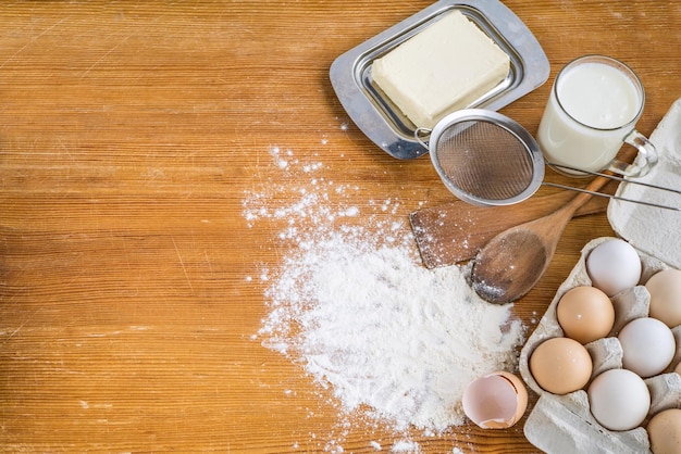 Chicken eggs in a cardboard tray near the kitchen utensils and scattered white flour on the table and a heart painted on the flour Cooking Cooking recipes