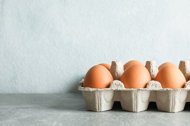 Chicken eggs in carton box on gray