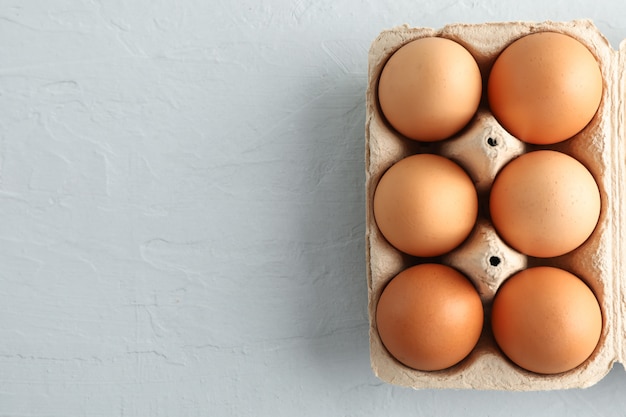 Chicken eggs in carton box on gray