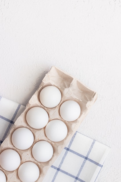 Chicken eggs on a checked kitchen towel on a light table