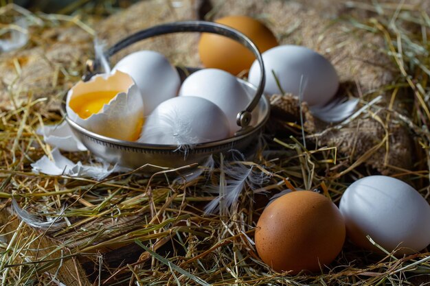 Photo chicken eggs on dry grass on an old background