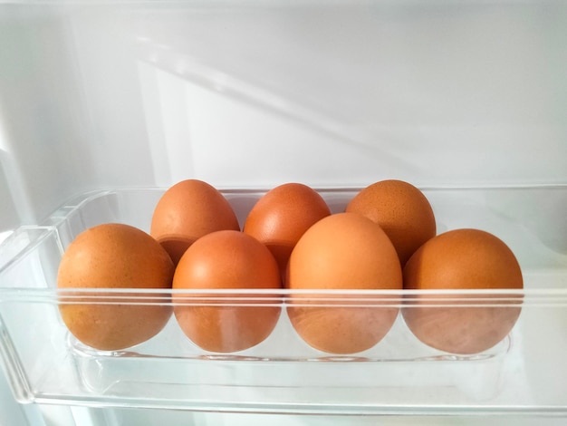 Chicken eggs on the fridge door of refrigerator. Selected focus.