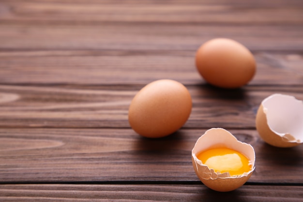 Chicken eggs and half with yolk on a brown background.