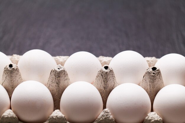 Chicken eggs in a package on a black table.