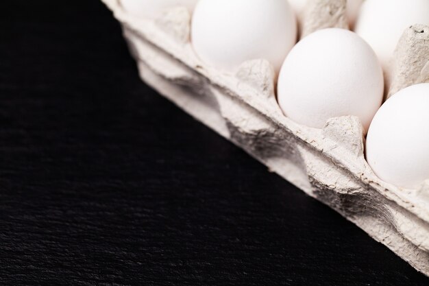 Uova di gallina in un pacchetto su un tavolo nero.