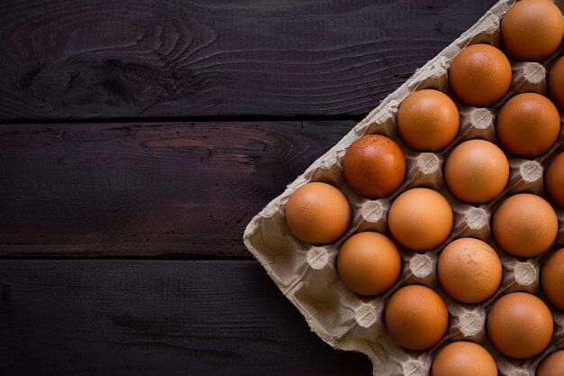 Chicken eggs in paper box on black wooden table