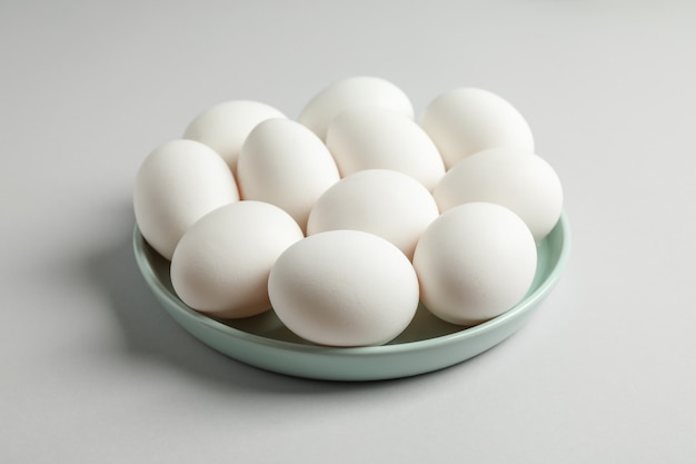 Chicken eggs in plate on gray