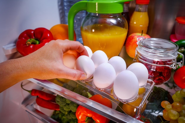 棚の開いた冷蔵庫の上の鶏の卵