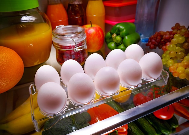 棚の開いた冷蔵庫の上の鶏の卵