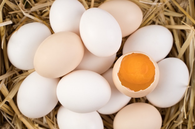 Chicken eggs of white and brown color with a broken egg in the center.
