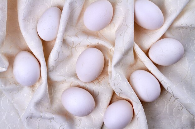 Chicken eggs on white ornamented textile cloth