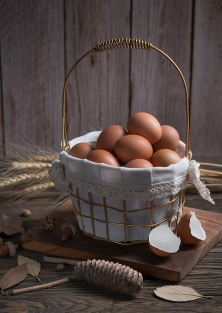 Chicken eggs in wire basket on wood background.