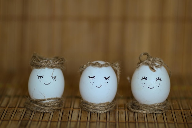 Chicken eggs with painted face on a brown background Handpainted eggs Easter eggs