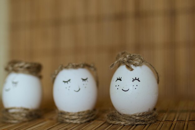 Куриные яйца с раскрашенным лицом на коричневом фоне Раскрашенные вручную яйца Пасхальные яйца
