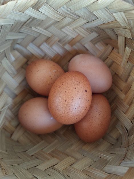 chicken eggs in a woven bamboo basket on a wooden table