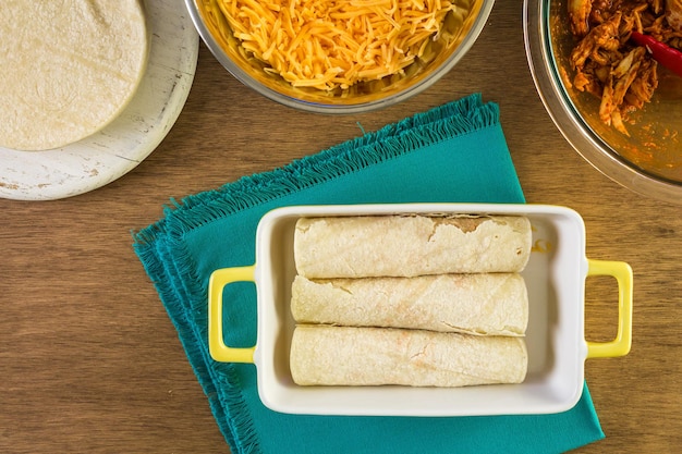 Chicken enchiladas with cheddar cheese and sauce.