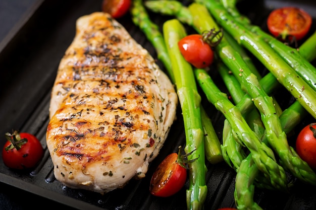 Photo chicken fillet cooked on a grill and garnish of asparagus.