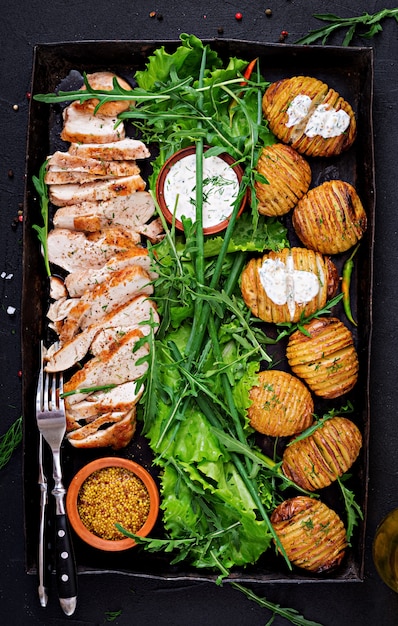 Chicken fillet cooked on a grill with a garnish of baked potatoes