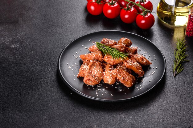 Chicken fillet in sesame seeds, teriyaki sauce on a black stone plate. Asian cuisine