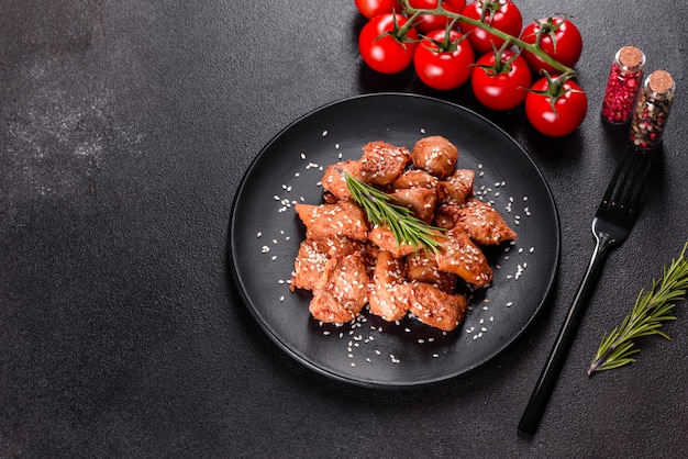 Chicken fillet in sesame seeds, teriyaki sauce on a black stone plate. Asian cuisine