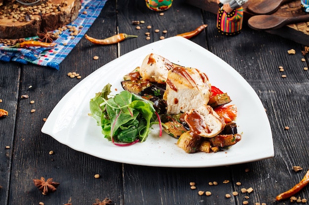 Chicken fillet with sauce and vegetables on the black wooden table