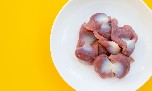 Foto gizzard di pollo in piastra bianca su sfondo giallo