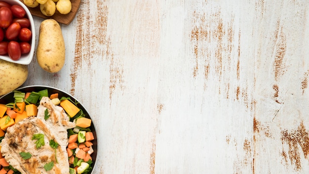 Photo chicken on griddle and vegetables on grunge painted desk