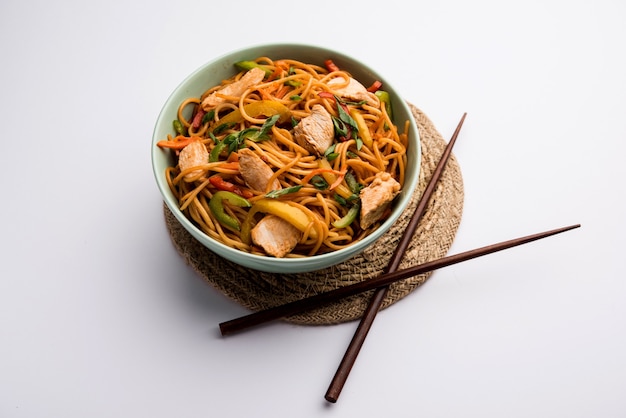 Chicken Hakka or Schezwan noodles served in a bowl with chopsticks. selective focus