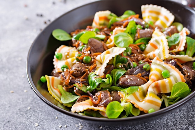 Chicken hearts with carrots in sweet and sour sauce with farfalle pasta. Healthy salad