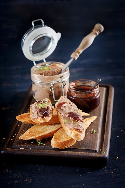 Chicken homemade liver paste or pate in glass jar with toasts and lingonberry jam with chili. 