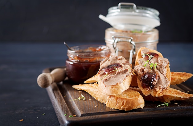 Chicken homemade liver paste or pate in glass jar with toasts and lingonberry jam with chili.