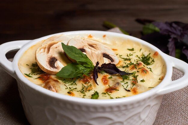 Julienne di pollo con funghi e erbe aromatiche in piatto bianco su tavola di legno