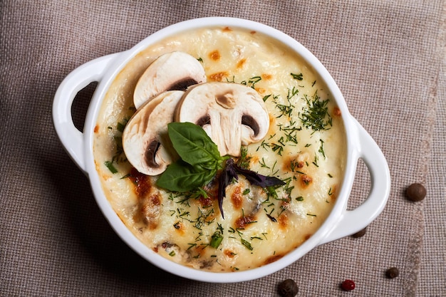 Foto julienne di pollo con funghi e erbe aromatiche in piatto bianco su tavola di legno