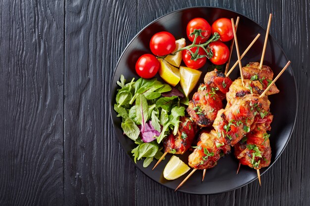 Chicken kebab grilled on skewers served with salad