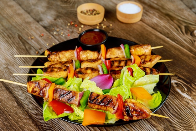 Chicken kebab on wooden skewer with salad and sauce