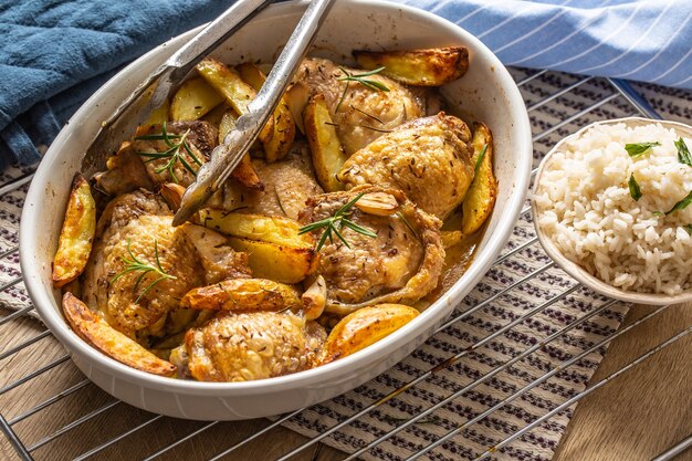Chicken legs roasted with american potatoes in baking dish.