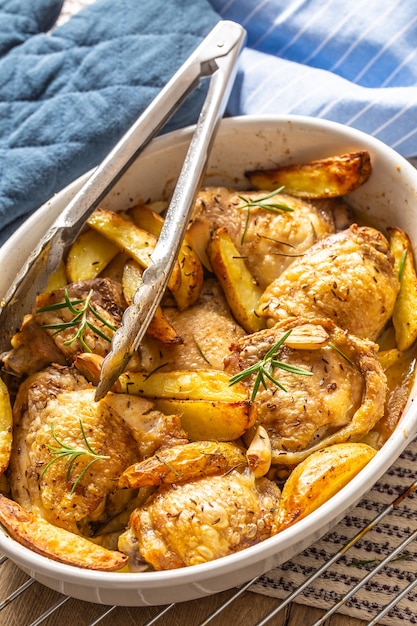 Chicken legs roasted with american potatoes in baking dish.