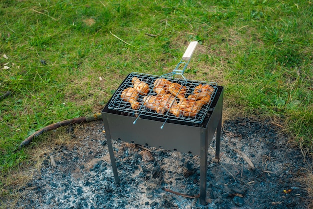 Le cosce e le ali di pollo vengono fritte sulla brace in un braciere in un barbecue pollo marinato viene fritto durante un picnic