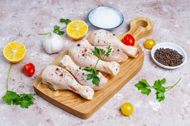 Куриные ножки со специями и солью готовы для приготовления пищи на разделочной доске.