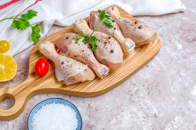 Chicken legs with spices and salt ready for cooking on cutting board.