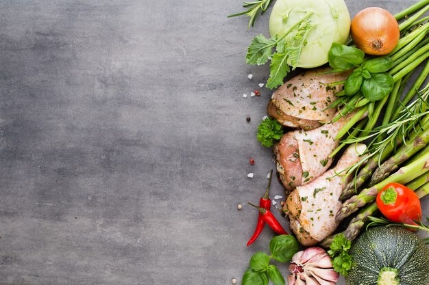 Chicken marinade legs, fresh vegetables on a gray background.Top view.