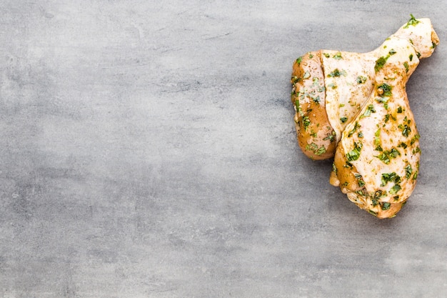 Chicken marinade legs, fresh vegetables on a gray surface.Top view.