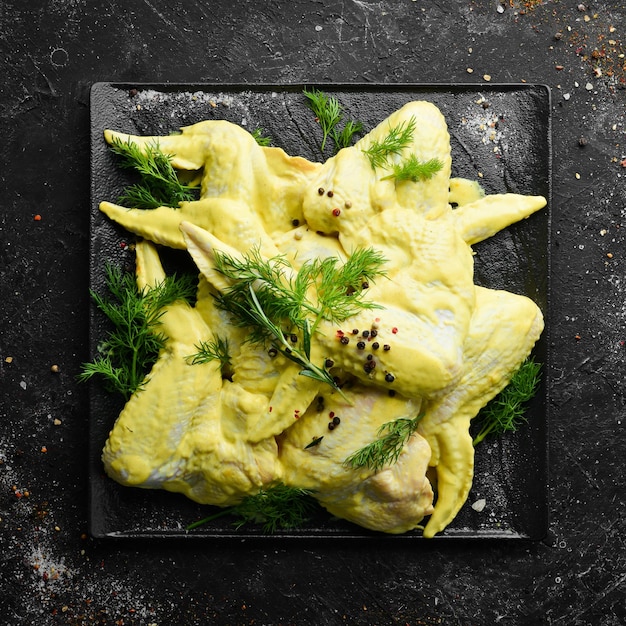 Chicken marinated in mustard sauce and spices on a black plate Top view Free copy space
