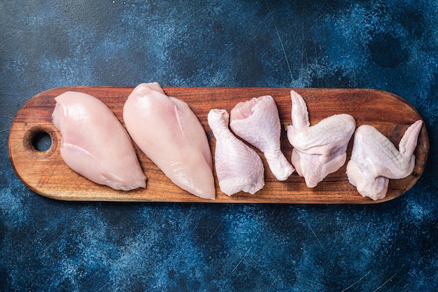 Photo chicken meat assortment raw parts drumstick breast fillet wings thigh blue background top view