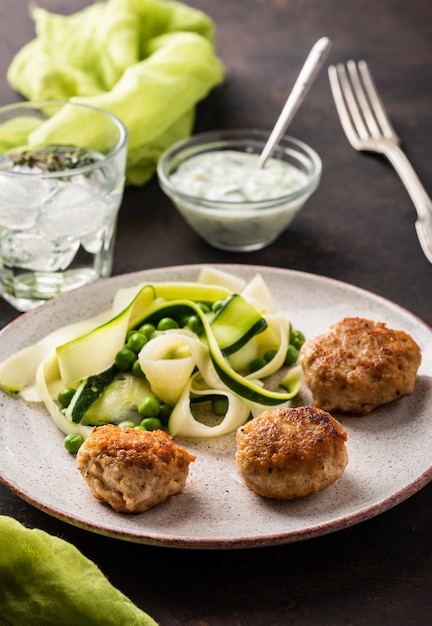 Chicken meat balls with zucchini salad and green peas, with garlic-yogurt sauce.