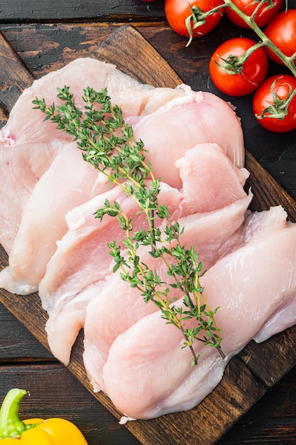 Chicken meat slices uncooked, on old dark  wooden table background