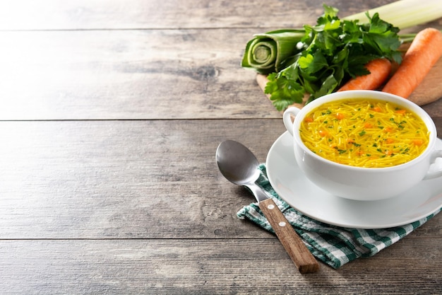 Chicken noodle soup in white bowl on wooden table