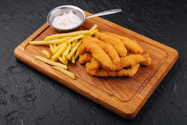 Chicken nuggets and french fries on wooden board