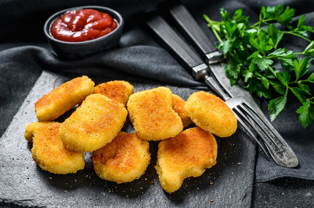 Photo chicken nuggets and ketchup sauce on the blackboard. dark background. top view